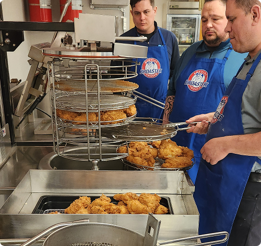 Chef Ken training two people on the E-Series 24G. He is taking chicken off the fryer racks.